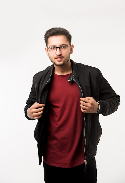 Indischer asiatischer junger Mann, der eine Brille oder eine Brille hält, während er über weißem Hintergrund steht
