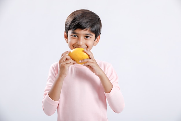 Indischer / asiatischer kleiner Junge, der Mango isst
