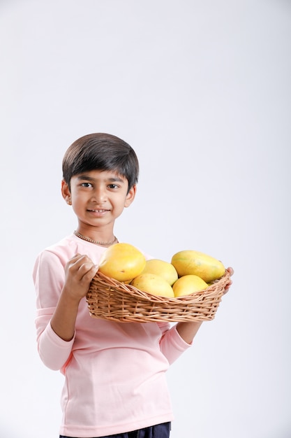 Indischer / asiatischer kleiner Junge, der Mangokorb in der Hand hält