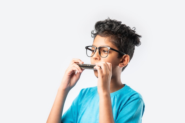 Indischer asiatischer kleiner Junge, der Mundharmonika oder Mundharmonika spielt, Konzept des frühen Lernens