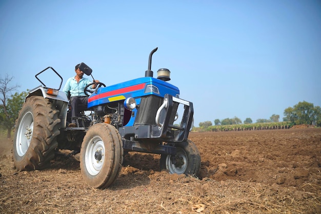 Indischer Bauer, der mit Traktor auf dem Gebiet der Landwirtschaft arbeitet.