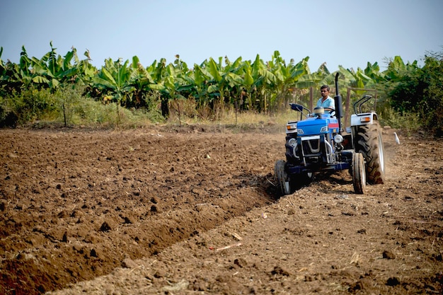 Indischer Bauer, der mit Traktor auf dem Gebiet der Landwirtschaft arbeitet.