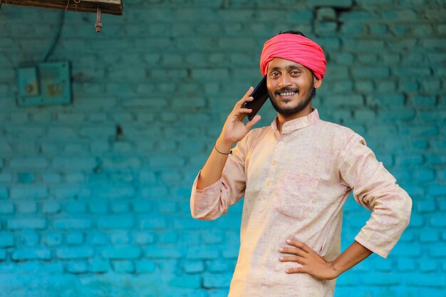 Foto indischer bauer, der zu hause am smartphone spricht.