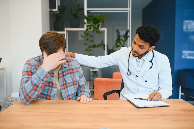 Indischer Doktor im weißen Kleid, das Patienten im Büro sieht