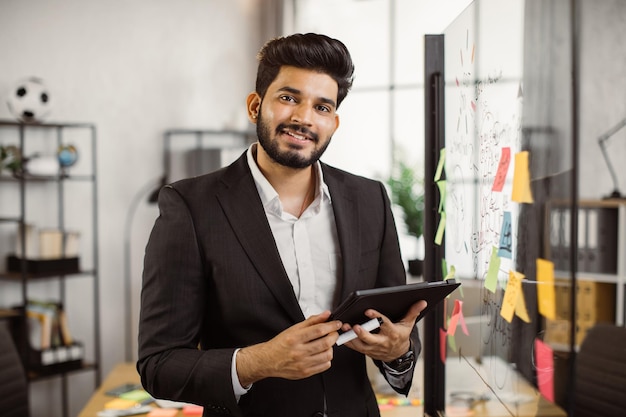 Indischer Geschäftsführer, der im Büro mit Laptop arbeitet