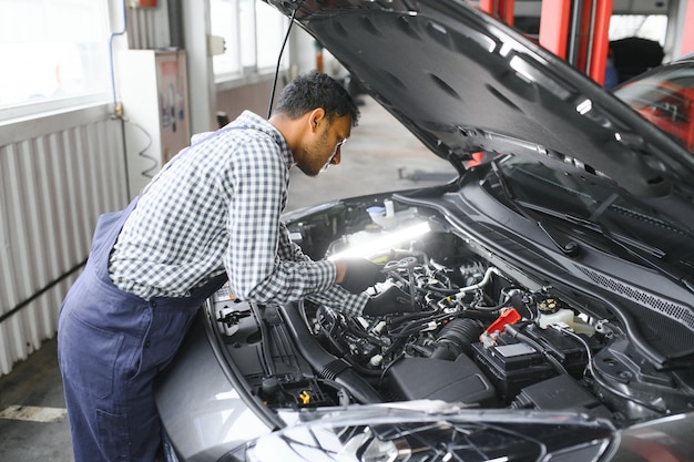 Indischer glücklicher Automechaniker im blauen Anzug