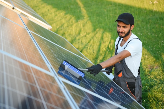 Indischer Handwerker reinigt Sonnenkollektoren und bildet Staub und Schmutz