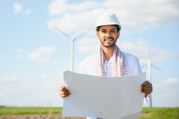 Indischer Ingenieur im Weizenfeld, der die Turbinenproduktion überprüft