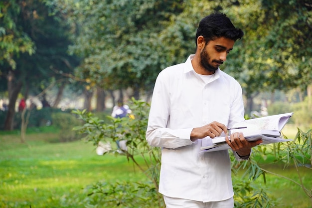 Foto indischer junge mit buchstift und stehen in der nähe des college-campus