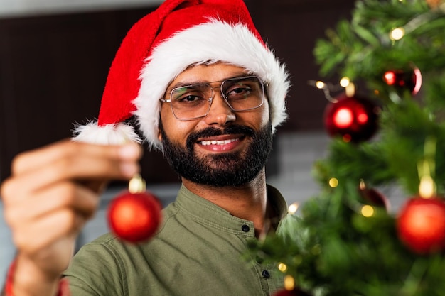 Indischer Mann in Sankt-Hut, der Weihnachtsbaum mit Flitter verziert