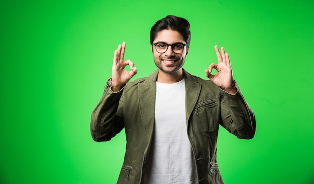 Indischer Mann mit Brille, T-Shirt und Jacke tragend, isoliert stehend standing