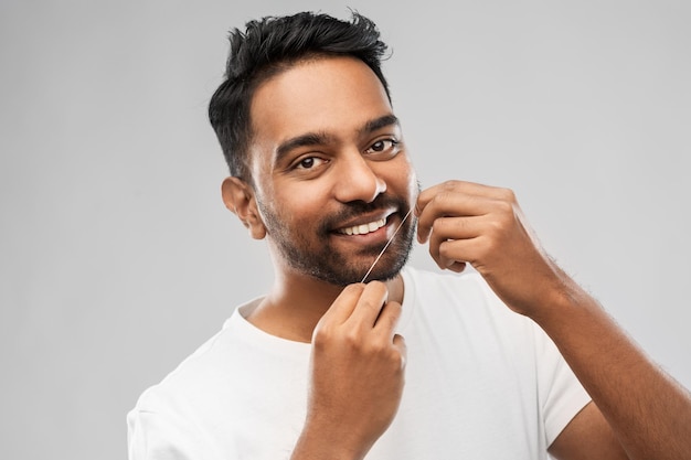 indischer Mann mit Zahnseide, der Zähne reinigt