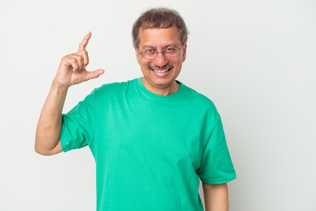 Indischer Mann mittleren Alters isoliert auf weißem Hintergrund, der etwas Kleines mit den Zeigefingern hält, lächelnd und selbstbewusst.
