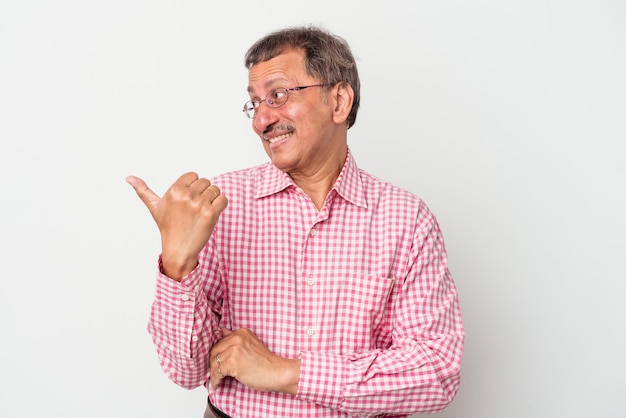 Indischer Mann mittleren Alters isoliert auf weißem Hintergrund zeigt mit Daumenfinger weg, lachend und sorglos.