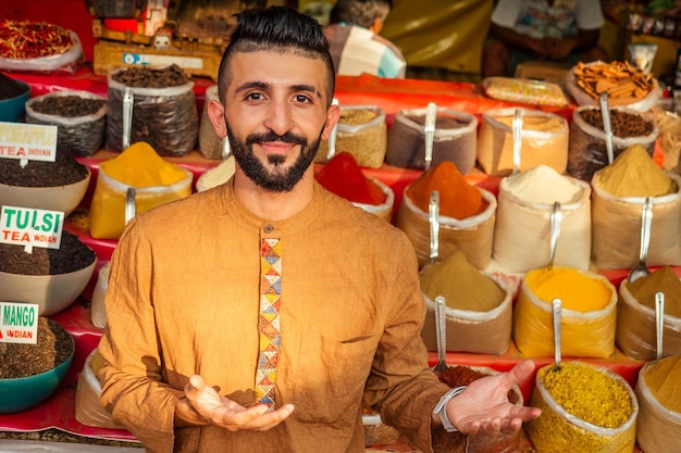 Indischer sallerman, der seinen kleinen laden auf dem markt von arambol goa zeigt