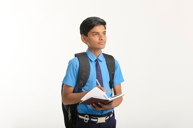 Indischer Schuljunge in Uniform und mit Tagebuch in der Hand auf weißem Hintergrund