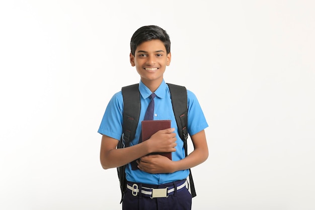 Indischer Schuljunge in Uniform und mit Tagebuch in der Hand auf weißem Hintergrund