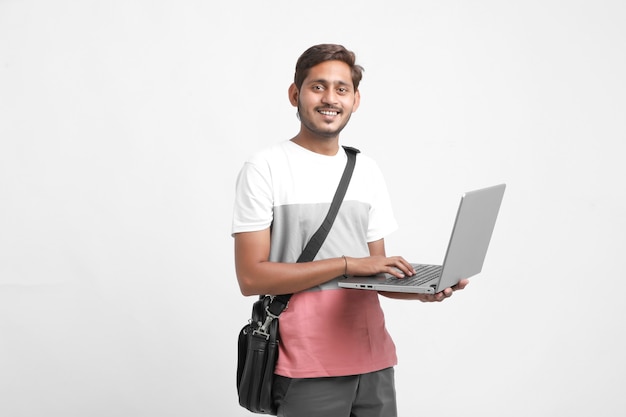 Indischer Student, der Laptop auf weißem Hintergrund verwendet.