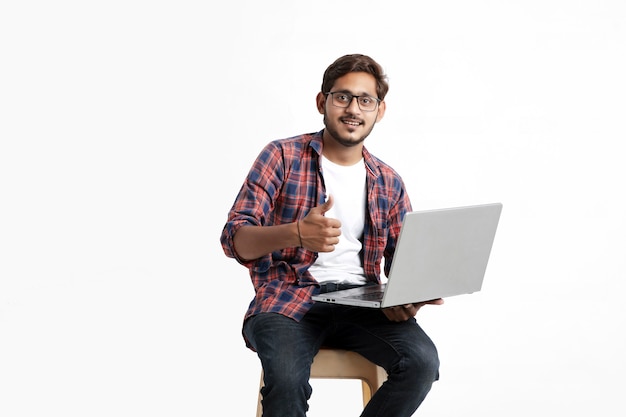 Indischer Student, der Laptop auf weißer Wand verwendet