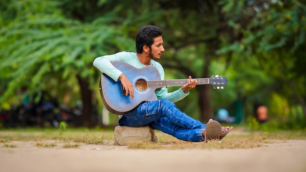 Indischer trauriger Junge, der Gitarre spielt
