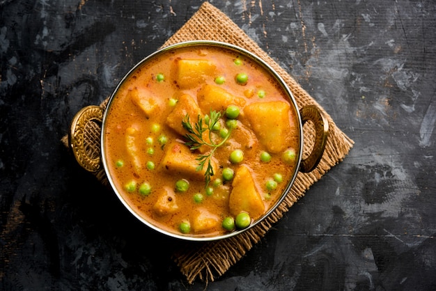 Indisches Aloo Mutter Curry - Kartoffel und Erbsen in einer Zwiebel-Tomaten-Soße eingelegt und mit Korianderblättern garniert. Serviert in einem Karahi oder Kadhai oder einer Pfanne oder Schüssel