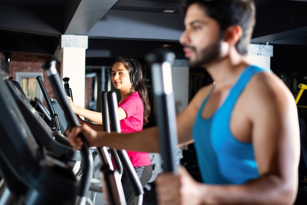 Indisches asiatisches attraktives Paar, das ein Cardio-Trainingsprogramm im Fitnesscenter oder im Fitnessstudio macht, selektive Focys - Gesundheits- und Fitnesskonzept