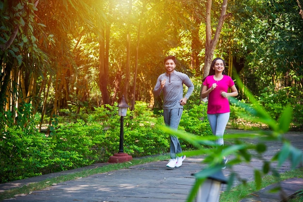 Indisches asiatisches junges Paar, das im Park oder in der Natur joggt, sich im Freien trainiert oder dehnt?