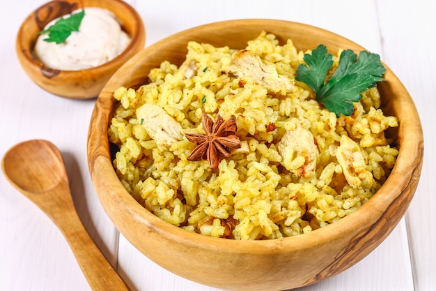 Foto indisches biryani mit huhn, joghurt, gewürzplatte auf einem holztisch. silvester, weihnachtsgericht.