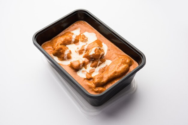 Indisches Butter-Hühnchen-Curry-Gericht, serviert in einem schwarzen Plastikbehälter für die Lieferung von Lebensmitteln nach Hause