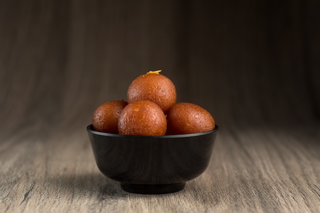 Indisches Dessert oder süßes Gericht Gulab Jamun in einer Schüssel auf Holz.