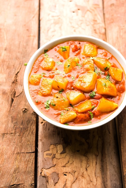 Indisches Essen - Aloo Curry Masala. Kartoffel gekocht mit Gewürzen und Kräutern in einem Tomatencurry. serviert in einer Schüssel über stimmungsvollem Hintergrund. selektiver Fokus