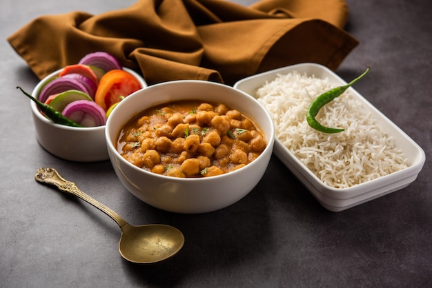 Indisches Essen Chole Chawal oder würziges Kichererbsen-Curry mit einfachem Reis, serviert mit grünem Salat. selektiver Fokus