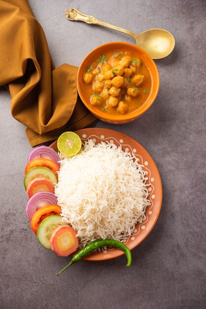 Indisches Essen Chole Chawal oder würziges Kichererbsen-Curry mit einfachem Reis, serviert mit grünem Salat. selektiver Fokus