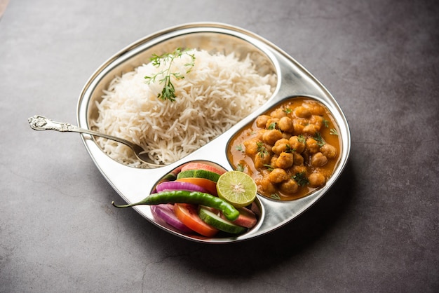 Indisches Essen Chole Chawal oder würziges Kichererbsen-Curry mit einfachem Reis, serviert mit grünem Salat. selektiver Fokus