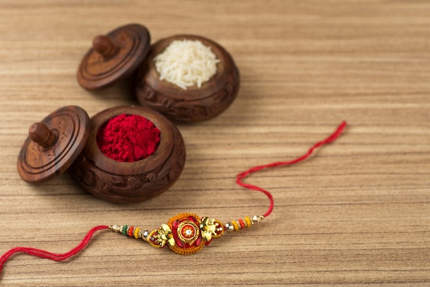 Indisches Festival: Raksha Bandhan Hintergrund mit einem eleganten Rakhi, Reiskörner und Kumkum