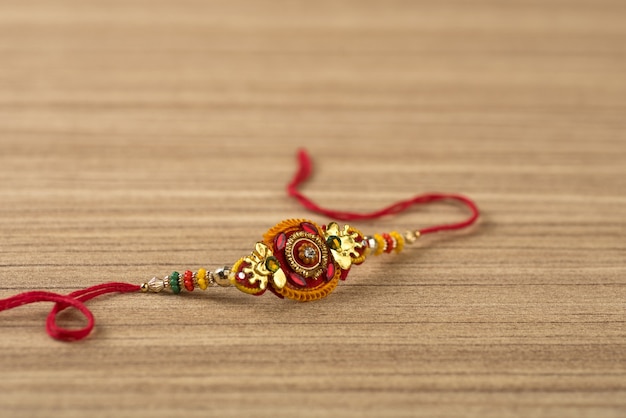 Indisches Festival: Raksha Bandhan Hintergrund mit einem eleganten Rakhi, Reiskörner und Kumkum