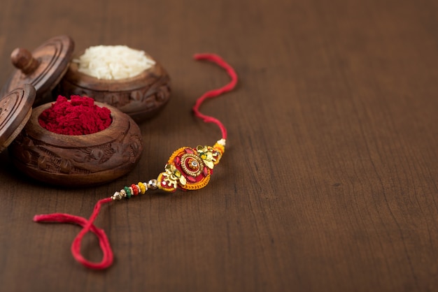 Indisches Festival: Raksha Bandhan Hintergrund mit einem eleganten Rakhi, Reiskörner und Kumkum