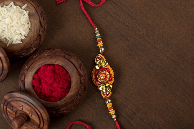 Indisches Festival: Raksha Bandhan Hintergrund mit einem eleganten Rakhi, Reiskörner und Kumkum