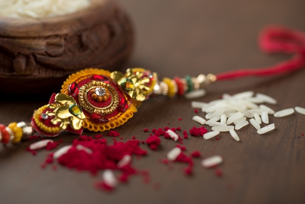 Indisches Festival: Raksha Bandhan Hintergrund mit einem eleganten Rakhi, Reiskörner und Kumkum