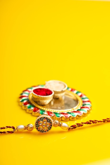 Indisches Festival Raksha Bandhan Puja Thali und Rakhi oder Armband auf gelbem Hintergrund