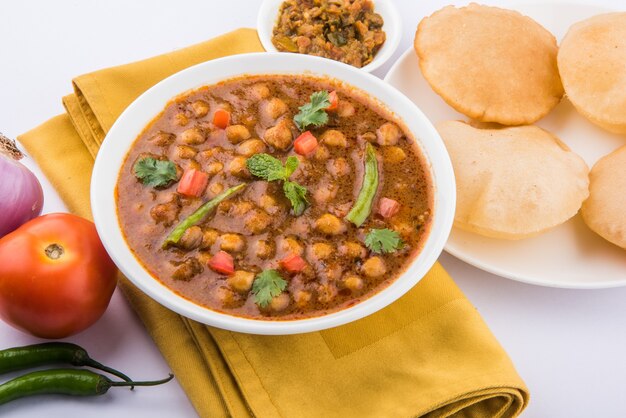 Indisches Gericht würziges Kichererbsen-Curry, auch bekannt als Chola oder Chana Masala oder allgemein Chole, serviert mit gebratenem Puri oder Poori auf buntem oder hölzernem Hintergrund. Selektiver Fokus