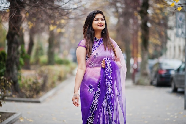 Indisches hinduistisches Mädchen im traditionellen violetten Saree posierte auf der Herbststraße