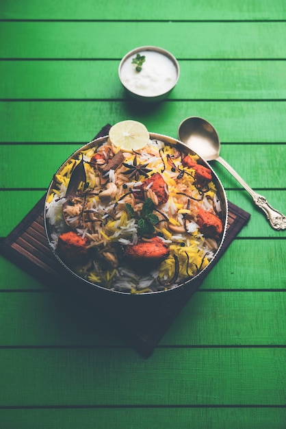 Indisches Hühnchen Tikka Biriyani serviert in einer Schüssel mit Joghurt. selektiver Fokus