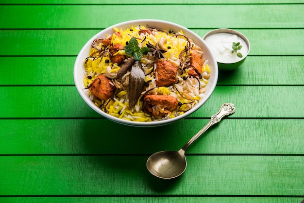 Indisches Hühnchen Tikka Biriyani serviert in einer Schüssel mit Joghurt. selektiver Fokus