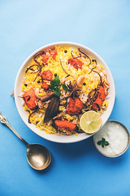 Indisches Hühnchen Tikka Biriyani serviert in einer Schüssel mit Joghurt. selektiver Fokus