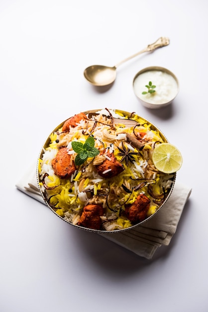 Indisches hühnchen tikka biriyani serviert in einer schüssel mit joghurt