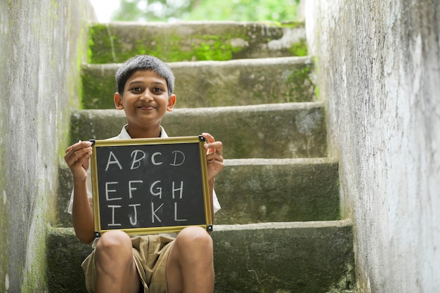 Indisches Kind, das ABCD-Alphabet auf Tafel schreibt