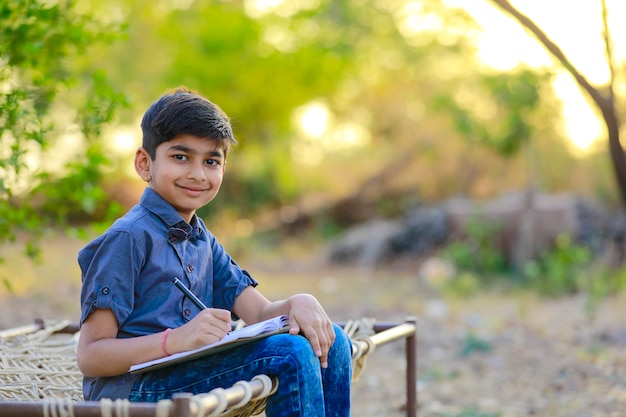 Indisches Kind, das auf Notizbuch schreibt