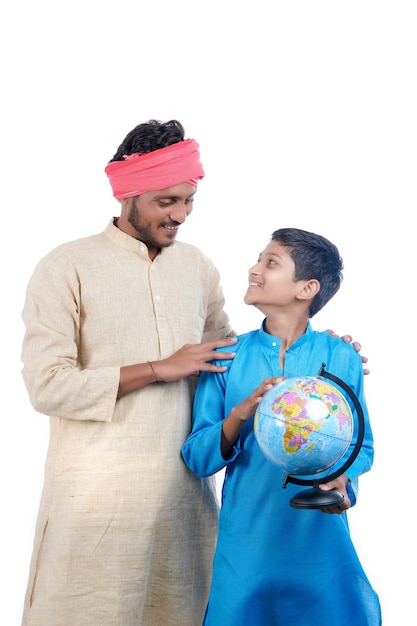 Indisches Kind, das Weltkugel in der Hand hält und sein Vater, der einige Informationen gibt.