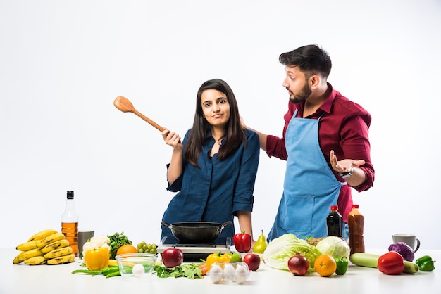 Indisches Paar in der Küche - Junge schöne asiatische Frau, die das Kochen mit Ehemann mit viel frischem Gemüse und Obst genießt